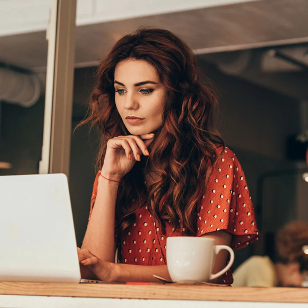 Female NCARB ARE Candidate studying Project Development and documentation exam at desk with a coffee.